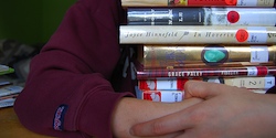 Arms around pile of books